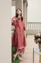 A woman in a pink dress stands gracefully on a balcony