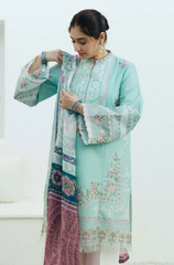 A woman wearing a mint green embroidered suit, standing confidently with a soft smile against a neutral background.