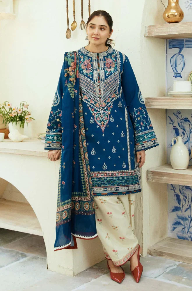 A woman wearing a blue and white embroidered suit, standing confidently with a serene expression.
