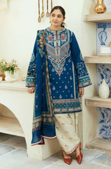 A woman wearing a blue and white embroidered suit, standing confidently with a serene expression.